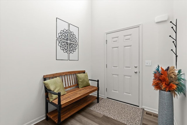doorway with baseboards, wood finished floors, and visible vents