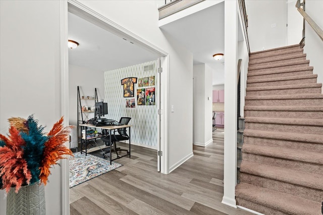 entryway with baseboards, light wood-style flooring, and stairway