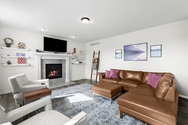 living room featuring baseboards, a fireplace, wood finished floors, and visible vents