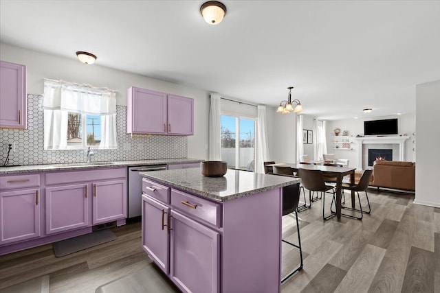 kitchen with an inviting chandelier, wood finished floors, dishwasher, a sink, and backsplash