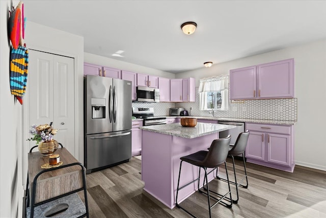 kitchen with a kitchen island, stainless steel appliances, a sink, and tasteful backsplash
