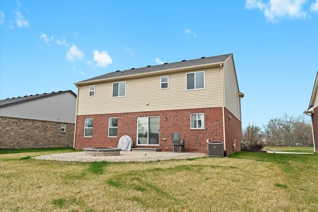 back of property with brick siding, a patio area, central AC, and a yard