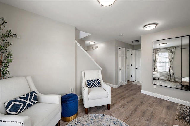 living area featuring stairs, baseboards, visible vents, and wood finished floors
