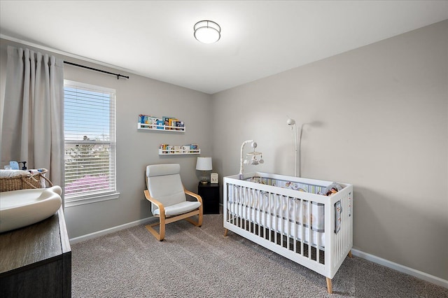 bedroom with carpet floors, baseboards, and a crib