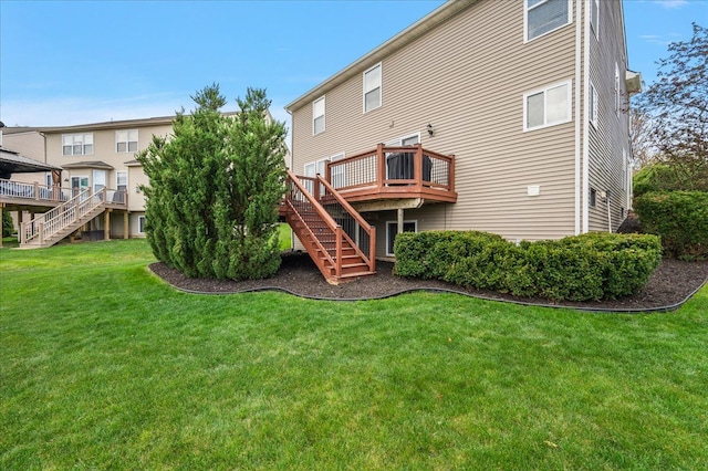 rear view of house with a yard, a deck, and stairs