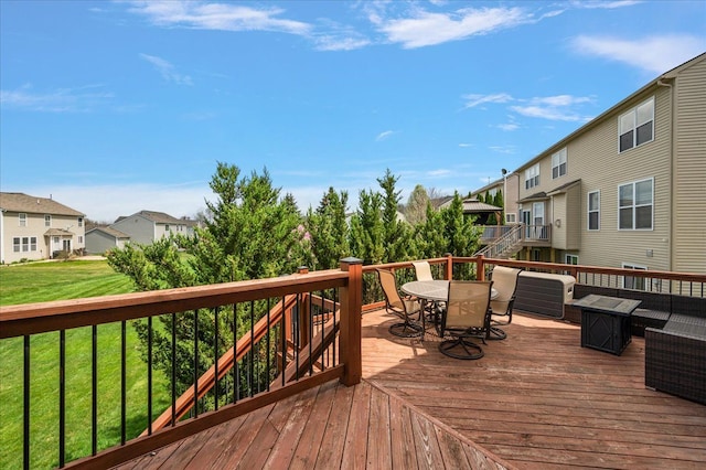 wooden deck featuring a lawn, stairs, a residential view, and outdoor dining space