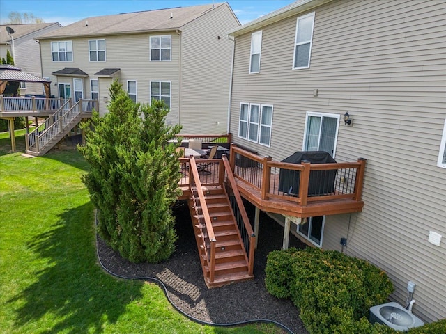 rear view of house with a lawn, a wooden deck, and stairs