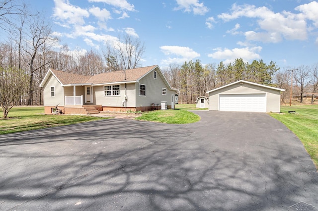 exterior space with a shingled roof, a garage, an outbuilding, covered porch, and a yard