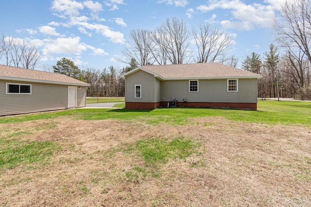 rear view of property with a shingled roof and a yard