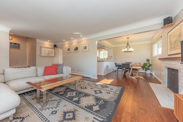 living room featuring an inviting chandelier, a brick fireplace, wood finished floors, baseboards, and baseboard heating