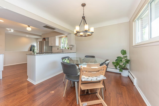 dining room with visible vents, dark wood-style flooring, baseboards, a baseboard heating unit, and a notable chandelier
