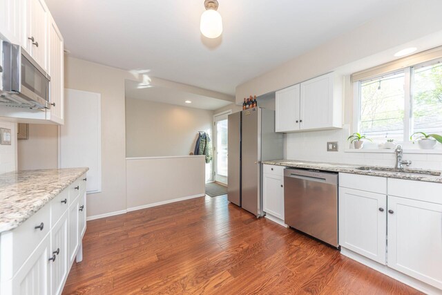 kitchen with white cabinets, appliances with stainless steel finishes, decorative backsplash, and a sink