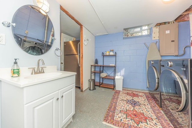 clothes washing area featuring laundry area, electric panel, a sink, independent washer and dryer, and concrete block wall