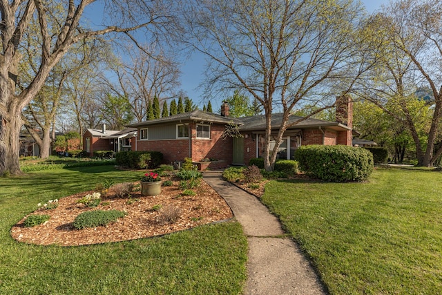 view of front of property with brick siding, a chimney, and a front yard