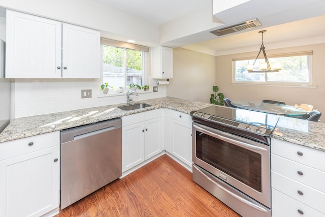 kitchen featuring visible vents, appliances with stainless steel finishes, a sink, white cabinets, and light wood finished floors