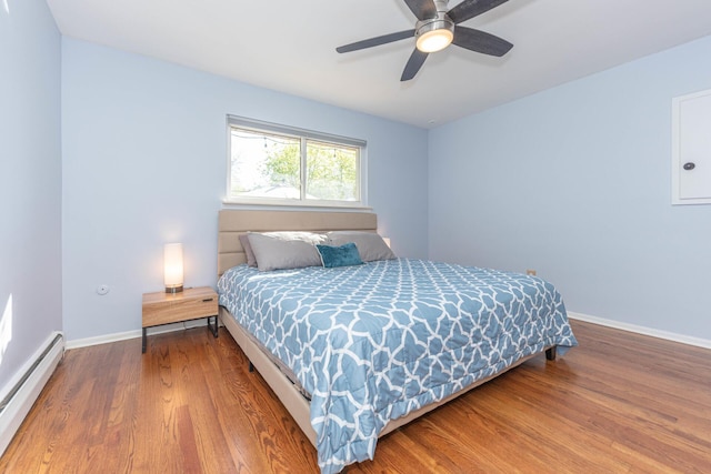 bedroom featuring a ceiling fan, baseboards, baseboard heating, and wood finished floors