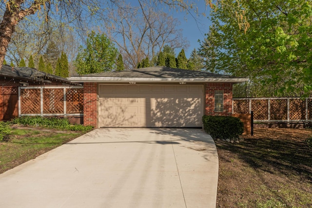 garage with fence and concrete driveway