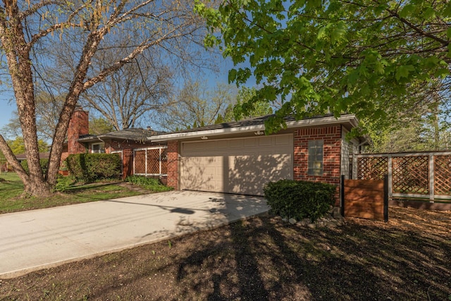 view of front of home featuring brick siding, a garage, a chimney, and concrete driveway