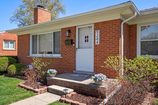 property entrance with brick siding and a chimney
