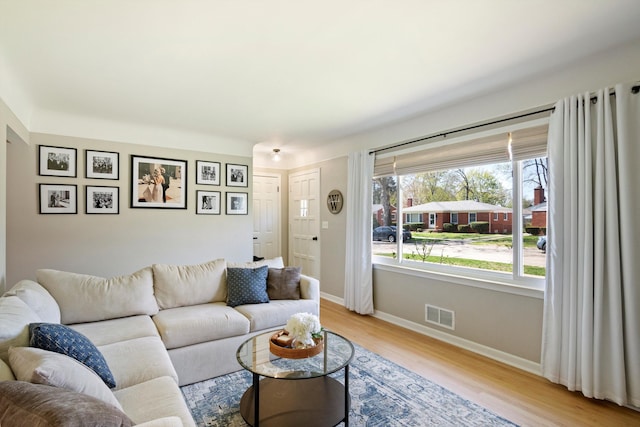 living room featuring baseboards, visible vents, and light wood-type flooring