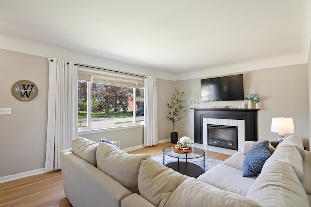living area with baseboards, a fireplace, and light wood finished floors