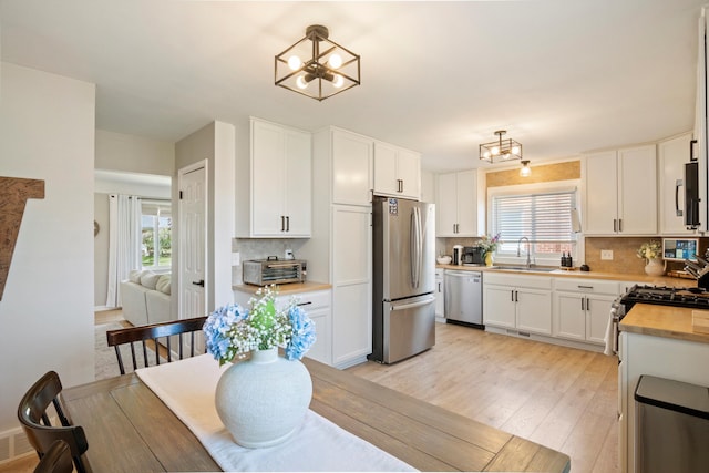 kitchen featuring a notable chandelier, appliances with stainless steel finishes, a wealth of natural light, and a sink