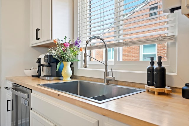 interior details featuring white cabinetry, a sink, and dishwasher
