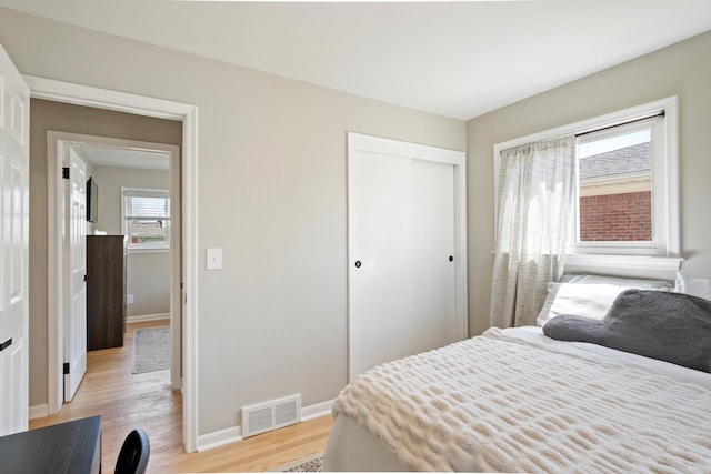 bedroom featuring a closet, baseboards, visible vents, and light wood-type flooring