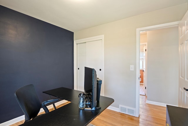 office space featuring visible vents, light wood-style flooring, and baseboards