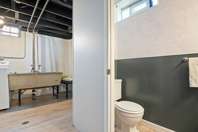 bathroom with washer / clothes dryer, toilet, a sink, and wood finished floors