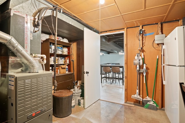 finished basement with heating unit and freestanding refrigerator