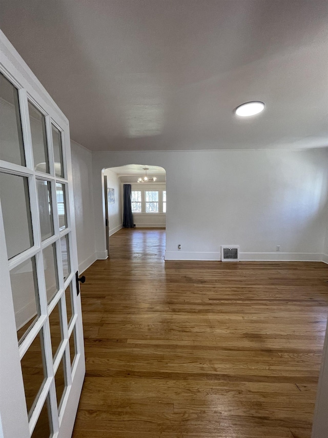unfurnished room featuring baseboards, visible vents, and wood finished floors