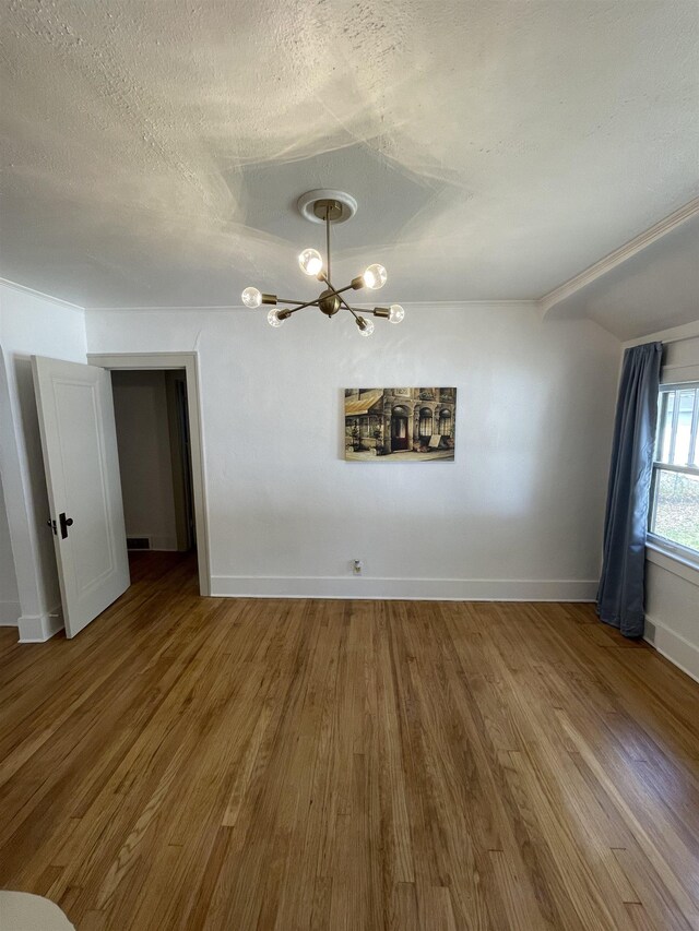 2314 Begole St, Flint, MI 48504 - spare room with a chandelier, wood finished floors, baseboards, a textured ceiling, and vaulted ceiling