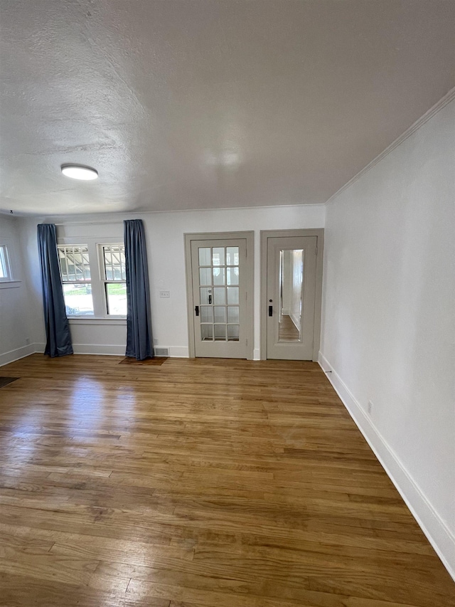 interior space with a textured ceiling, baseboards, and wood finished floors