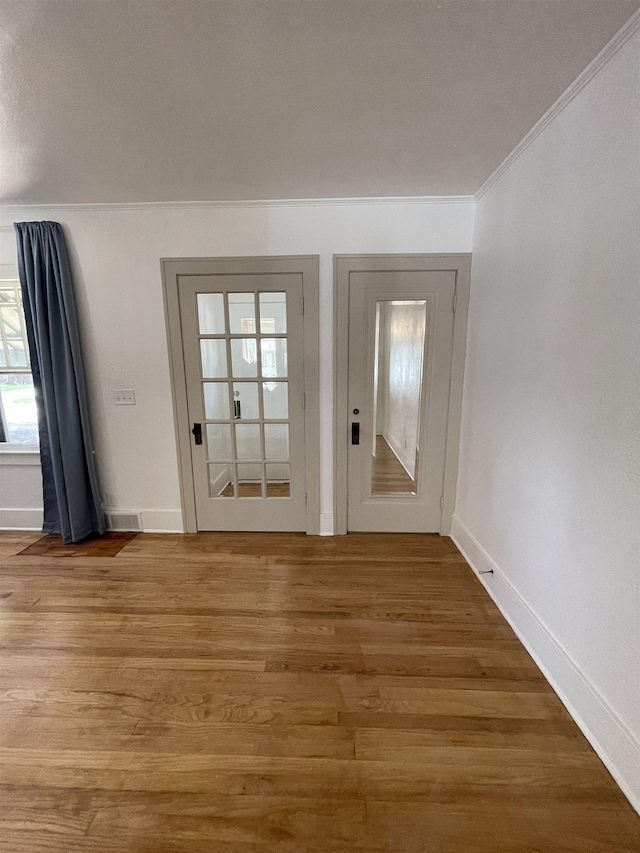 doorway with light wood-style floors, baseboards, and crown molding