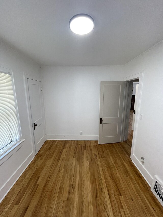 spare room featuring visible vents, baseboards, and wood finished floors