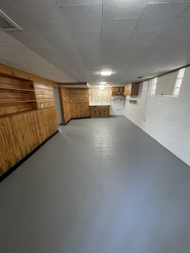 below grade area featuring concrete block wall, wood walls, and visible vents