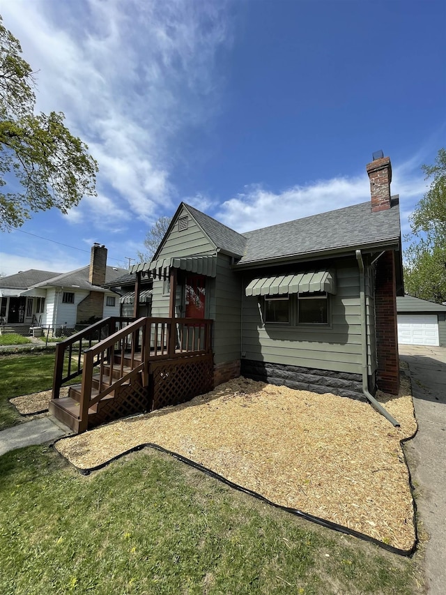 back of property with roof with shingles, a chimney, a deck, and a garage