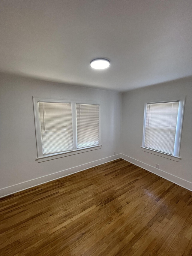 empty room with baseboards and dark wood-style floors