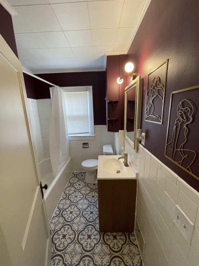 full bathroom featuring wainscoting, vanity, toilet, tile patterned floors, and tile walls