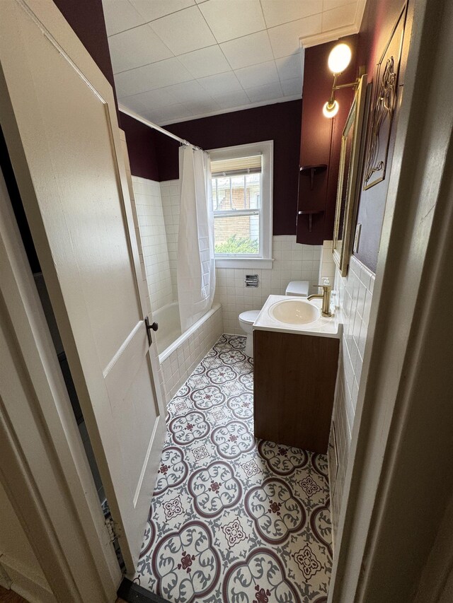 2314 Begole St, Flint, MI 48504 - bathroom featuring toilet, tiled shower / bath, vanity, tile walls, and a wainscoted wall