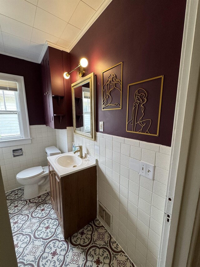 2314 Begole St, Flint, MI 48504 - half bathroom featuring tile walls, tile patterned floors, a wainscoted wall, toilet, and crown molding