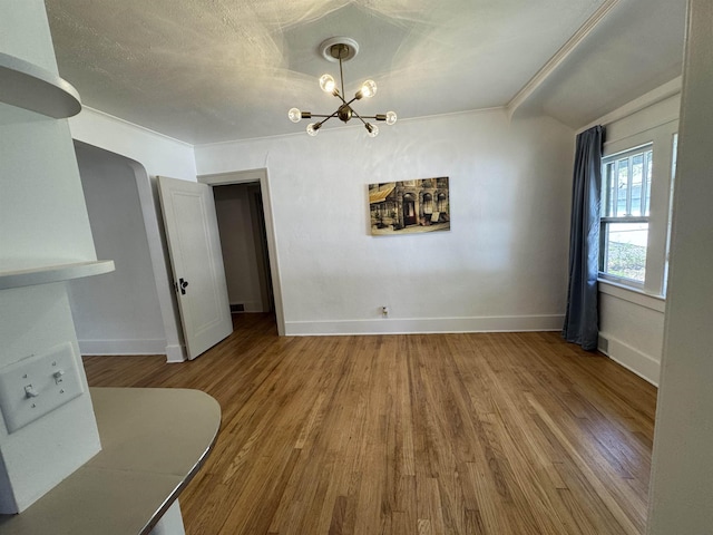 2314 Begole St, Flint, MI 48504 - unfurnished dining area with a chandelier, baseboards, and wood finished floors
