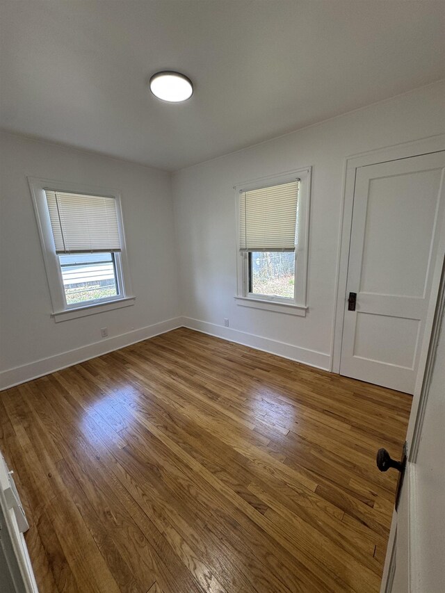 2314 Begole St, Flint, MI 48504 - empty room with healthy amount of natural light, wood finished floors, and baseboards