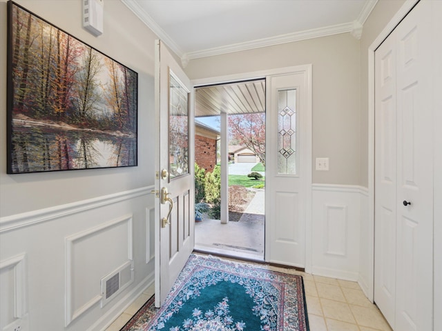 entrance foyer featuring crown molding, a wainscoted wall, a decorative wall, and visible vents
