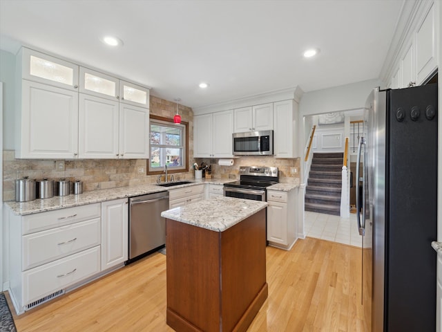 kitchen featuring light wood-type flooring, decorative backsplash, white cabinetry, and stainless steel appliances