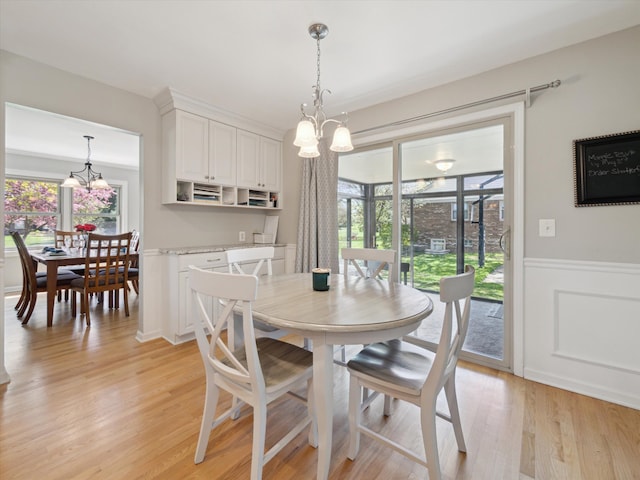 dining space with plenty of natural light, light wood finished floors, and a notable chandelier