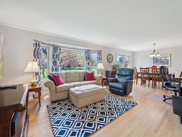 living area featuring a notable chandelier, ornamental molding, and light wood-style flooring