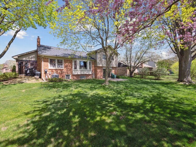 view of front of house featuring brick siding, a front lawn, and a chimney