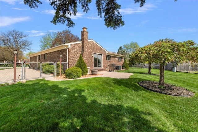rear view of house featuring fence, brick siding, a gate, a chimney, and a lawn